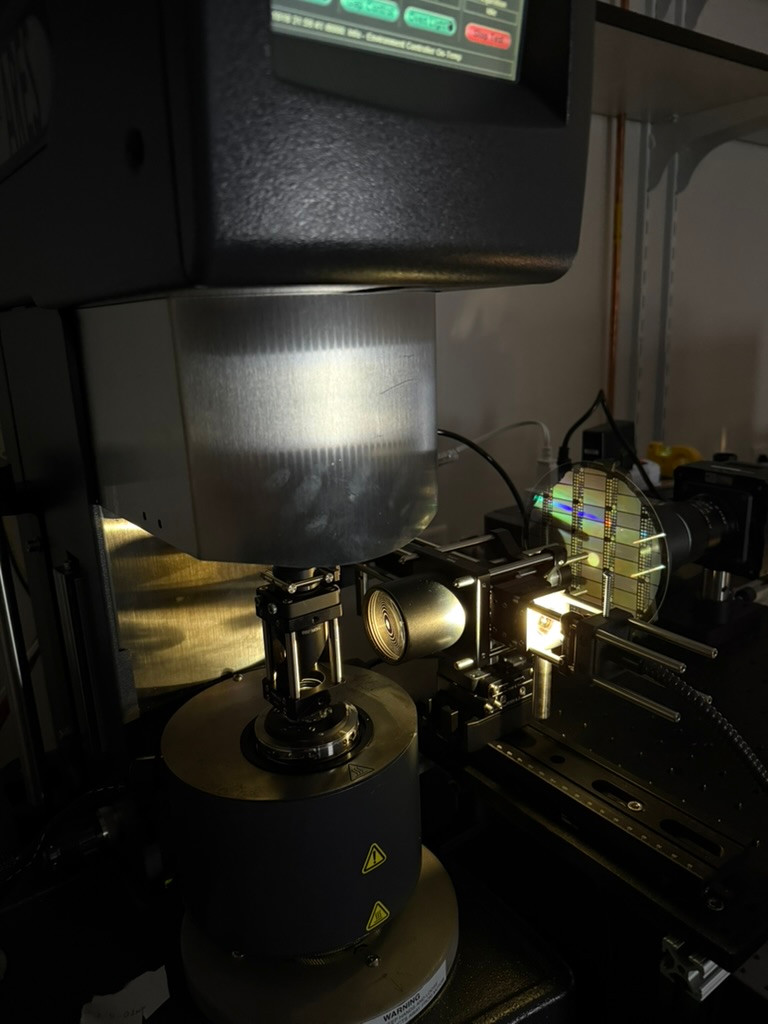 An instrument housing above a central fixture, with lenses, mounts, and an illuminated optical assembly to the right.
