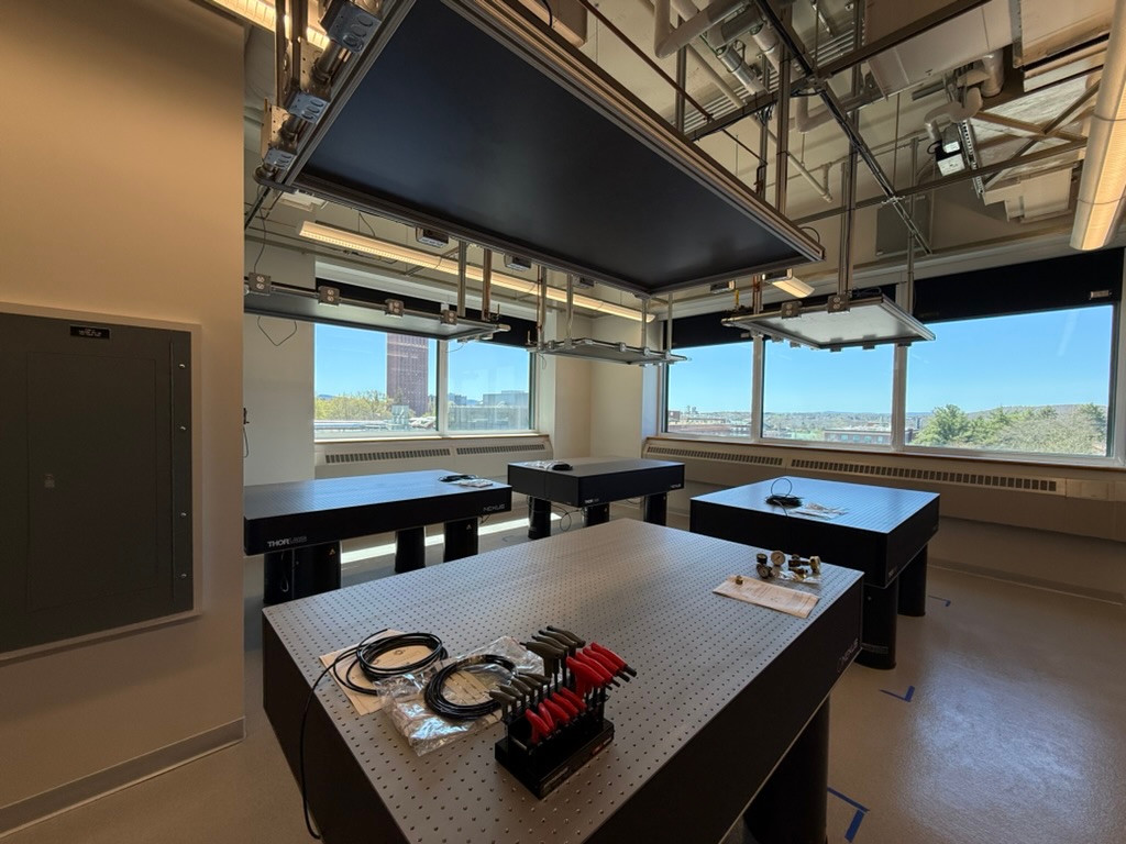 Optical tables in a laboratory, with tools and cables on the foreground table.